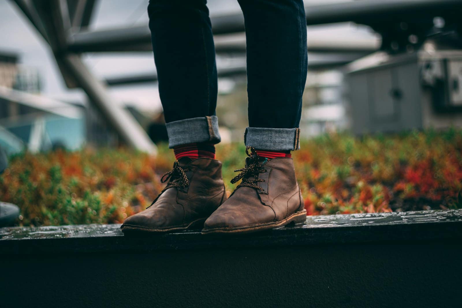 Brown leather boots standing on a dark wet platform, the sole edge wrapping continuously around the boot