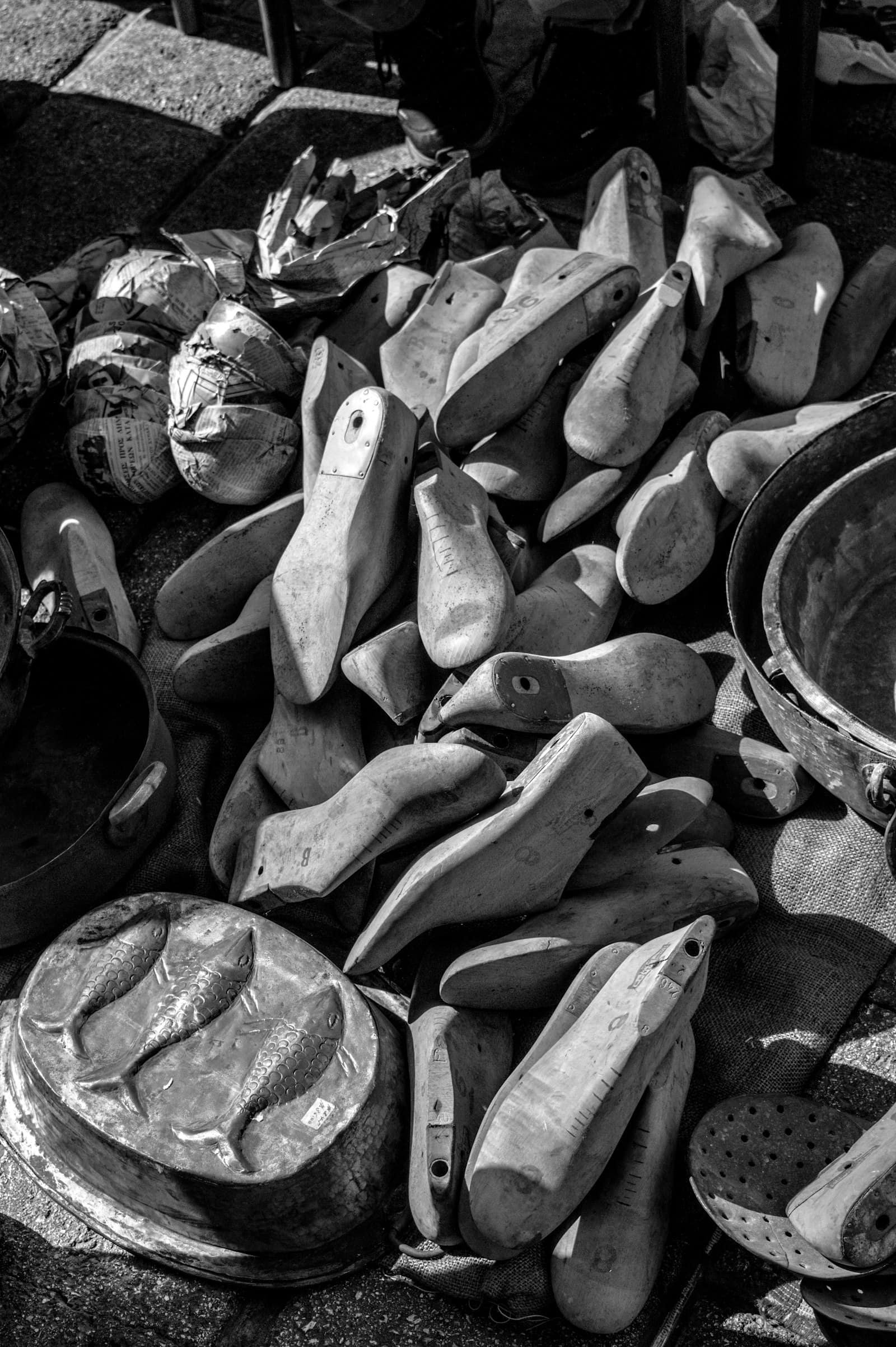 A heap of wooden shoe lasts on sacking, photographed in black and white