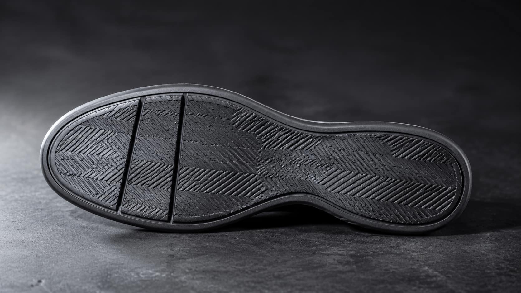 The underside of a vulcanised rubber outsole, herringbone tread and two flex grooves across the ball of the foot